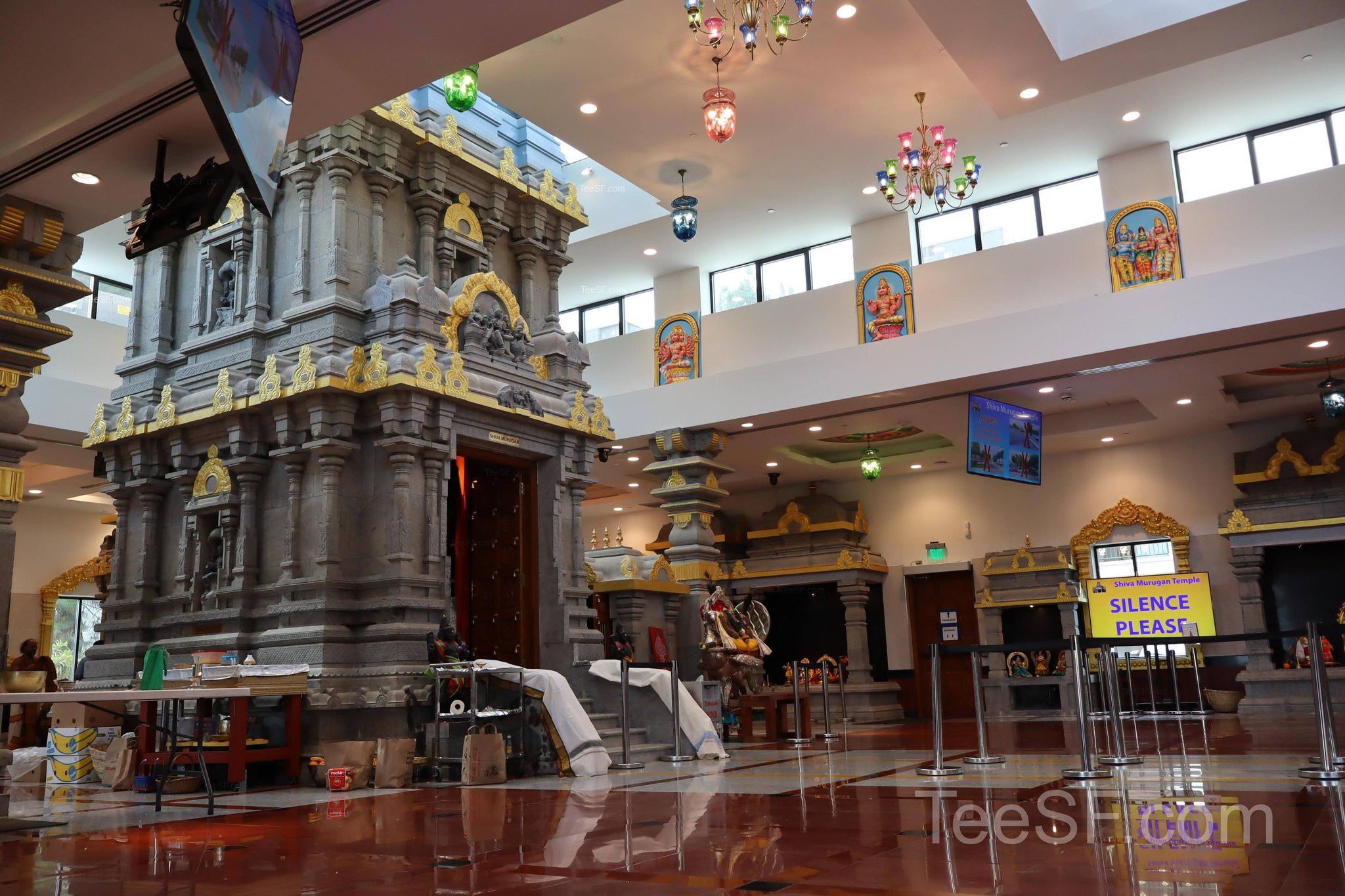 A wide view of the temple hall with carved stone shrines and soft light.